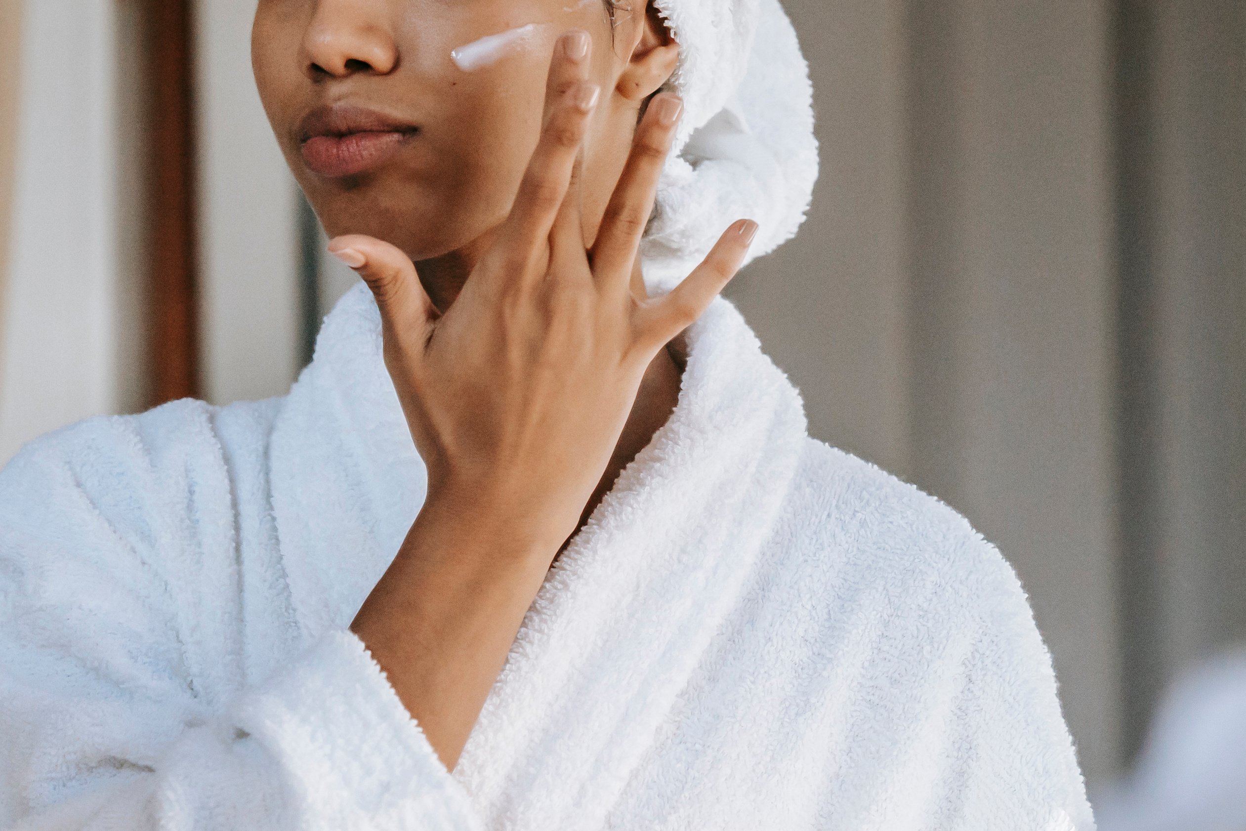 Woman applying cosmetic cream on face